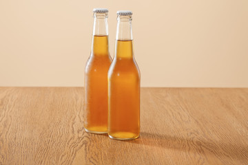 bottles of beer at wooden table isolated on beige