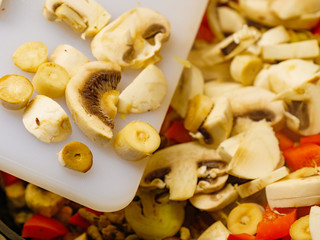 Adding mushrooms to pan vegetables.