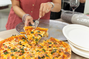 Woman hands using fork taking slices of pizza at dinner party.