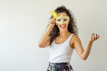 Young woman smiling holding carnival mask on white background