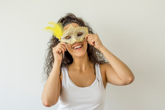 Young woman smiling holding carnival mask on white background