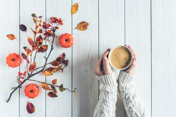 Woman with cup of coffee, leaves, small pumpkins and rowan on white retro wood boards. background. Autumn, fall concept. Flat lay, top view.