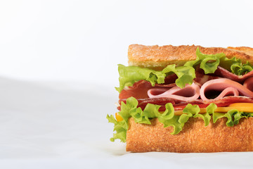fresh sandwich with lettuce, ham, cheese, bacon and tomato isolated on white