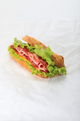 fresh sandwich with lettuce, ham, cheese, bacon and tomato on textured white background