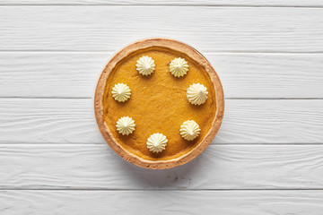 top view of delicious pumpkin pie with whipped cream on white wooden surface