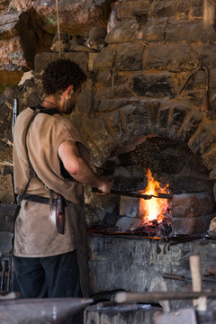 un forgeron devant le foyer en feu