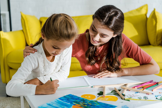 happy babysitter looking at drawing of cute kid