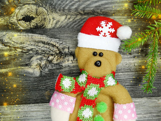 christmas fir tree branches with bear decoration on wooden background