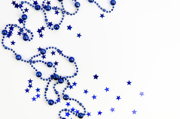 Background for winter celebrations decorated with blue Christmas tree beads and star shaped Sparkles isolated on white. Flat lay Mockup with copy space for text