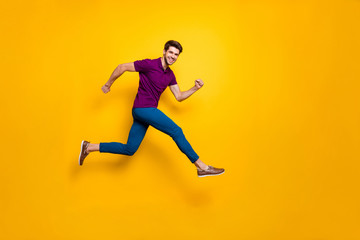 Fototapeta na wymiar Full lenghtb body size side profile photo of hurrying urgent white casual guy running jumping in blue pants trousers purple t-shirt footwear isolated over vivid color background