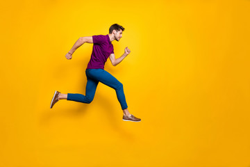 Fototapeta na wymiar Full length body size side profile photo of fast quick handsome man wearing blue pants trousers footwear running jumping to empty space isolated over vivid color background
