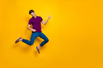 Fototapeta na wymiar Photo of cheerful crazy ecstatic overjoyed man pretending to be playing imaginary guitar wearing blue pants trousers shoes isolated over yellow vivid color background