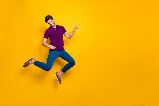 Photo of cheerful crazy ecstatic overjoyed man pretending to be playing imaginary guitar wearing blue pants trousers shoes isolated over yellow vivid color background