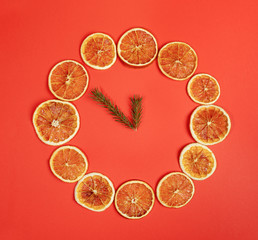 Creative X mas diy decor.  Dial of watch of handmade  dried orange slices with clock hands of fir twigs on red background.  Zero Waste Christmas concept.