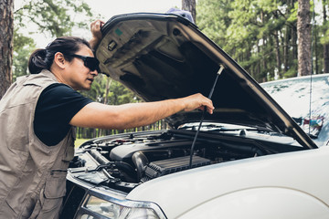 Asian man Opening the bonnet of his pickup truck to check the condition of the engine failure, to...
