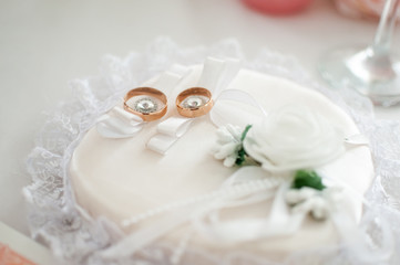 Pair of golden wedding rings on the white pillow