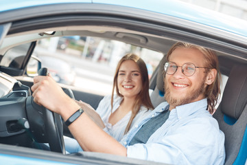 Young adult man and woman smiling and sitting in car