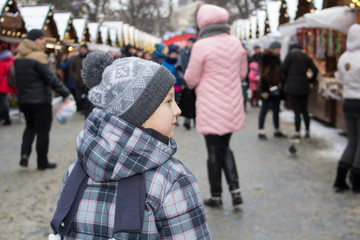 little boy with his back to the fair,little boy looked at his back while standing at the Christmas market in winter
