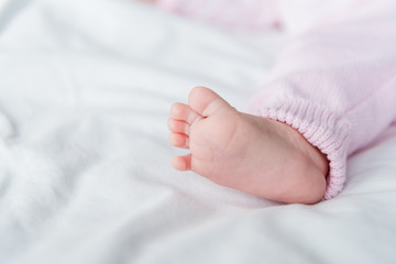 cropped view of small barefoot of infant baby lying on bed