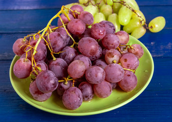 Bunch of red and green grapes in a plate on a wooden table.