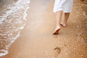 Fototapeta na wymiar Beatuful woman legs and feet walking on the sand of the beach.