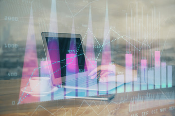 Double exposure of man's hands writing notes with laptop of stock market with forex graph background. Top View. Concept of research and trading.