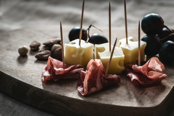 Winter and autumn starter  (aperitifs) with jamon, cheese, nuts and grapes on a wooden rustic...