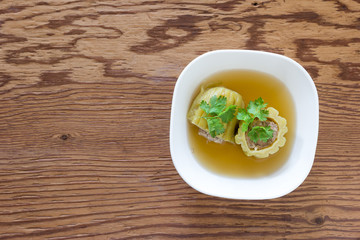 Stuffed bitter gourd soup with seasoned minced pork on wood background