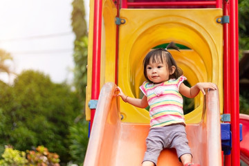 Asian child girl playing a slider toy at the playground. Happy Baby aged 2 years old.