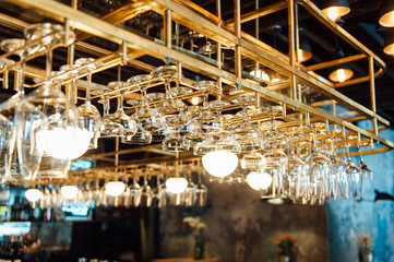 Clean washed and polished glasses hanging over a bar rack