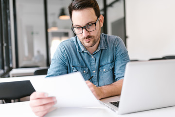 Close-up image of concentrated young man looking at paper document.
