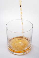 Close-up of an elegant glass for spirits, with a spilled liquor, similar to rum or whiskey, on a white background.