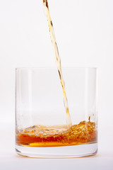 Close-up of an elegant glass for spirits, with a spilled liquor, similar to rum or whiskey, on a white background.