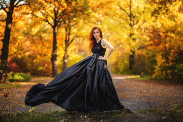 Fototapeta premium Woman is posing in colourful autumn park at sunset.
