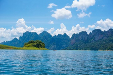Beautiful view from Ratchaprapa dam in Thailand. Beautiful landscape view with blue water, blue clouds sky and mountains at the background. Tourists in the boat are enjoying the view