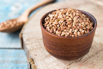 Uncooked buckwheat in a bowl on old boards. Buckwheat is used for cooking.