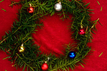 Fototapeta na wymiar Christmas tree branches stacked in a circle for the inscription Merry Christmas on a red background.