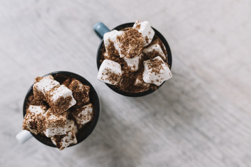 Two cups with marshmallows and cocoa powder