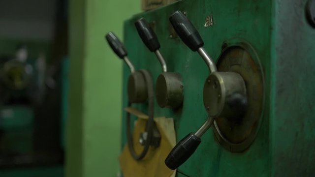 A factory equipment, a green mechanism with some buttons and regulators. Close up.