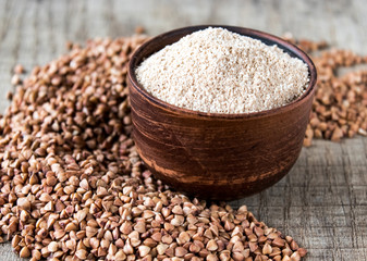 Buckwheat flour in a bowl near the buckwheat grain. A pile of buckwheat flour.