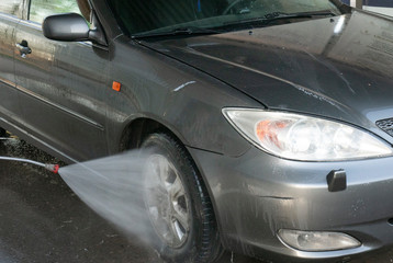 Fototapeta premium Close-up of a man washing his car with pressurized water in a car wash .