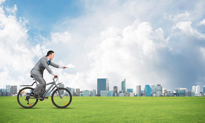 Businessman with paper documents in hand on bike