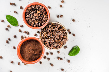 Small bowl of ground coffee and roasted coffee beans on white background, top view