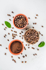 Small bowl of ground coffee and roasted coffee beans on white background, top view