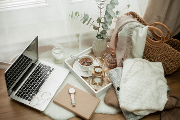 Fototapeta na wymiar Toned photo. Autumn decor. A laptop, a mug of hot tea, a bun, candles. Cozy. Autumn.