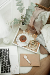 Toned photo. Autumn decor. A laptop, a mug of hot tea, a bun, candles. Cozy. Autumn.