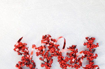 Christmas card with Holly berries, red ribbon on grey concrete background
