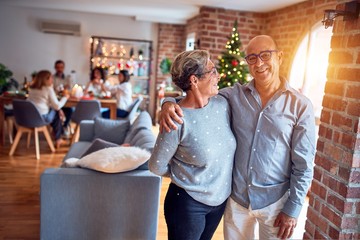 Family and friends dining at home celebrating christmas eve with traditional food and decoration, romantic senior couple hugging in love
