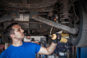 Car master mechanic repairer heating the screws with flamethrower burner