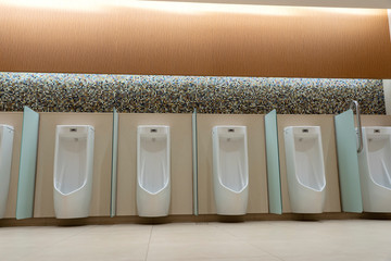 A row of urinals in tiled wall in a public restroom. Empty man toilet